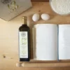 bottiglia olio accanto a uova e diario bianco